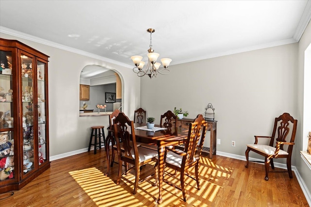 dining room with light wood-type flooring, an inviting chandelier, and crown molding