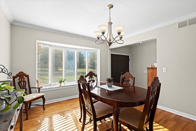 dining space with light wood-type flooring, an inviting chandelier, and ornamental molding