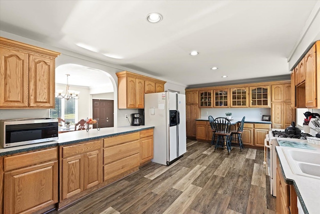 kitchen featuring pendant lighting, white appliances, dark wood-type flooring, crown molding, and a chandelier