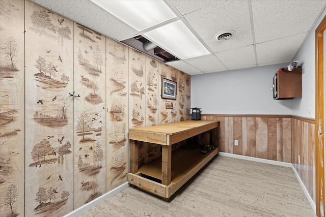 interior space with a drop ceiling, wood-type flooring, and wooden walls