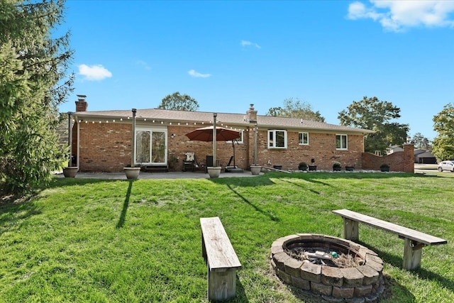 rear view of house featuring a yard, an outdoor fire pit, and a patio area