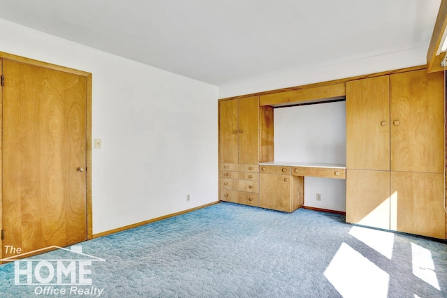 unfurnished bedroom with built in desk and light colored carpet