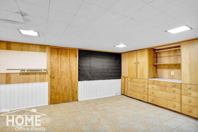 empty room with wooden walls, light floors, radiator heating unit, and a wainscoted wall