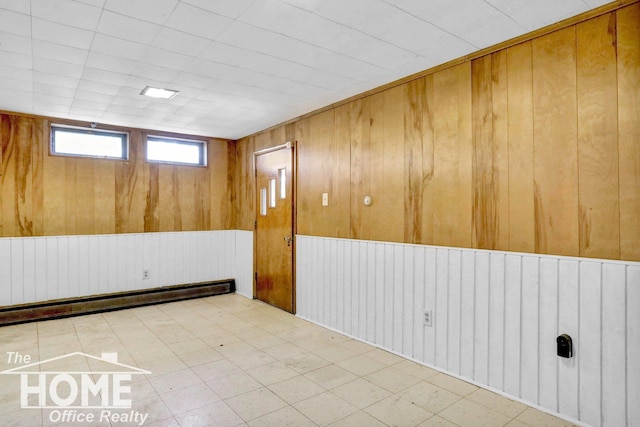 unfurnished room with a baseboard radiator and wooden walls