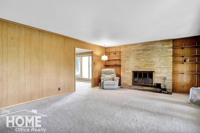 unfurnished living room with built in shelves, a stone fireplace, light carpet, and wood walls