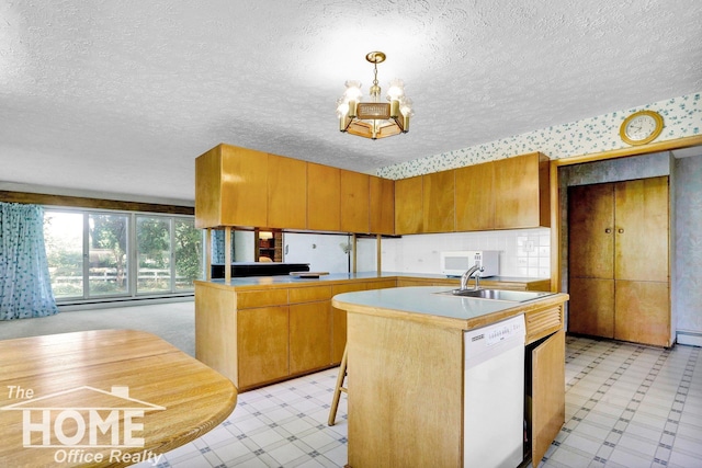 kitchen with sink, white appliances, a notable chandelier, decorative light fixtures, and kitchen peninsula