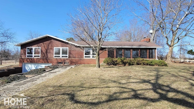 exterior space with a sunroom, a chimney, a front lawn, a garage, and brick siding