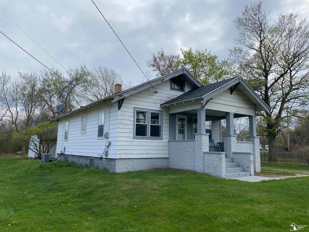 bungalow-style house featuring cooling unit, a porch, and a front yard