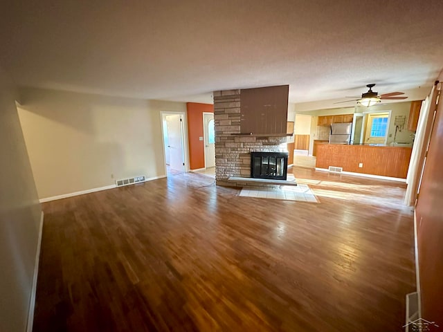 unfurnished living room with a textured ceiling, ceiling fan, light hardwood / wood-style floors, and a fireplace