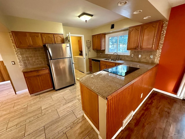 kitchen featuring tasteful backsplash, kitchen peninsula, sink, and appliances with stainless steel finishes