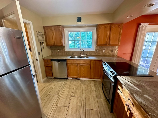 kitchen with sink, light wood-type flooring, tasteful backsplash, stone countertops, and stainless steel appliances