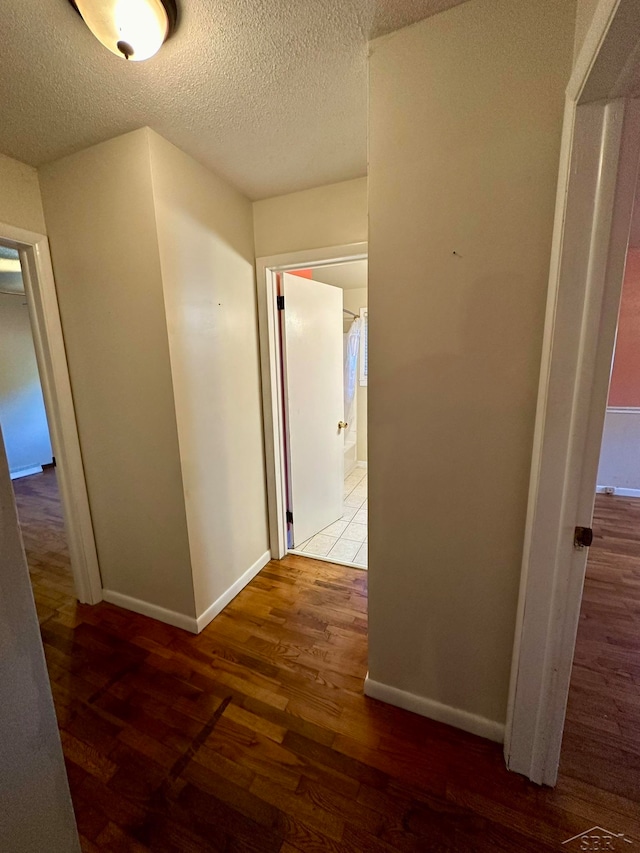 corridor featuring a textured ceiling and dark wood-type flooring