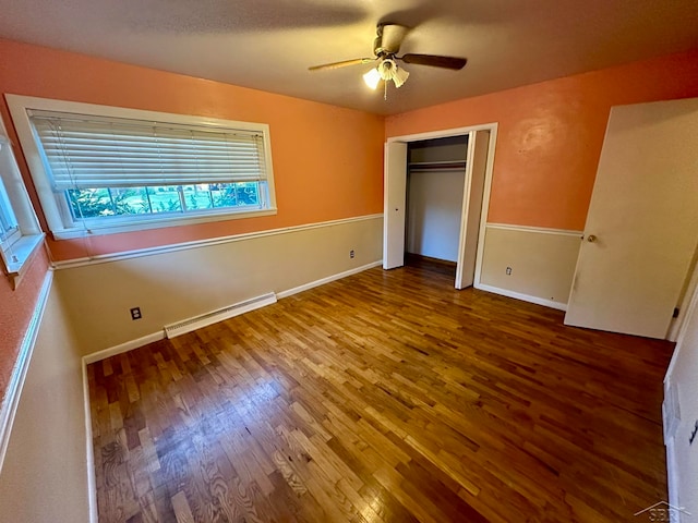 unfurnished bedroom with ceiling fan, a closet, wood-type flooring, and a baseboard heating unit