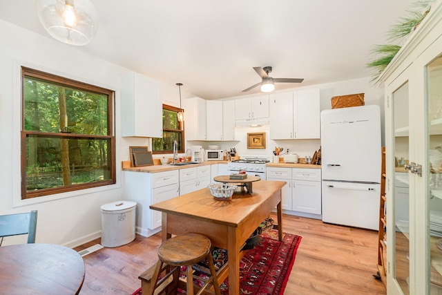 kitchen with white cabinetry, sink, light hardwood / wood-style floors, decorative light fixtures, and white appliances