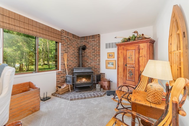 sitting room featuring a wood stove and carpet floors