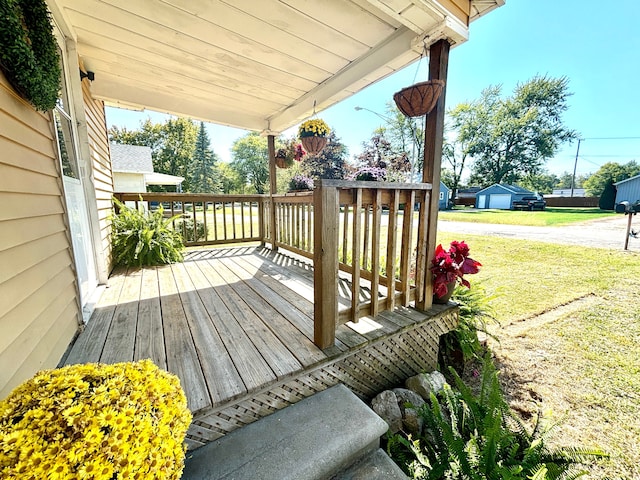 wooden terrace with a lawn and a porch