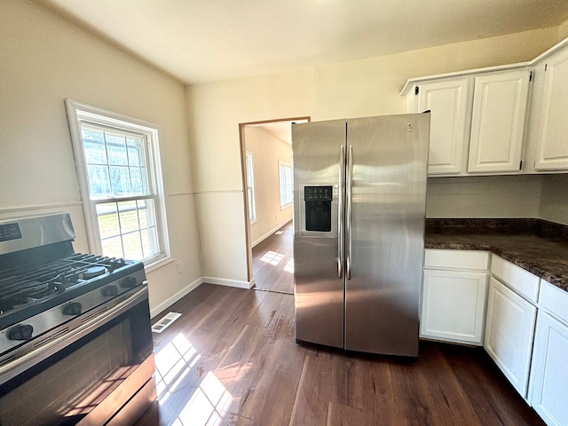 kitchen with white cabinets, dark hardwood / wood-style floors, appliances with stainless steel finishes, and dark stone counters