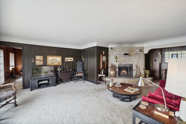 carpeted living room featuring wooden walls, a fireplace, and ornamental molding