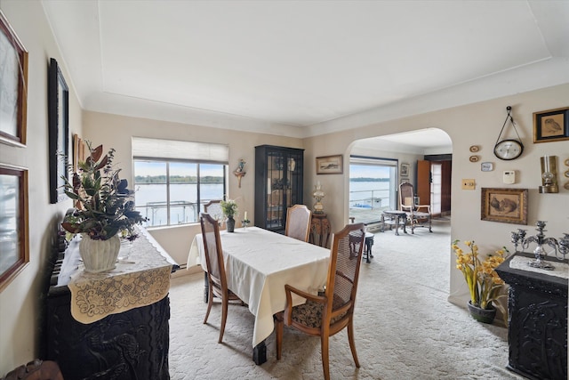 carpeted dining area with a water view