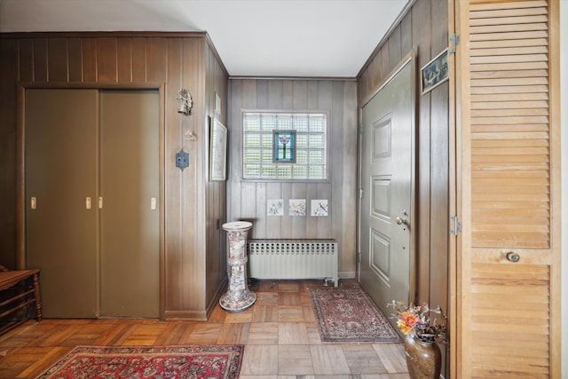 mudroom with wood walls, radiator heating unit, and parquet flooring