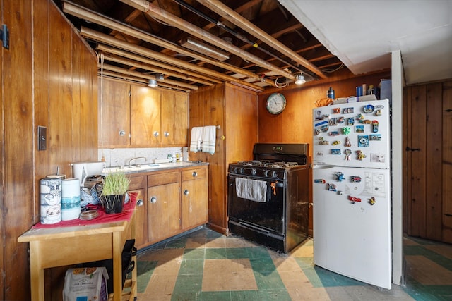 kitchen featuring wood walls, white refrigerator, black gas stove, and sink