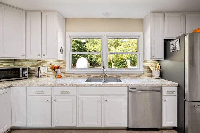 kitchen with backsplash, sink, white cabinetry, and stainless steel appliances