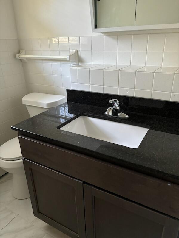 bathroom with vanity, tile walls, and toilet