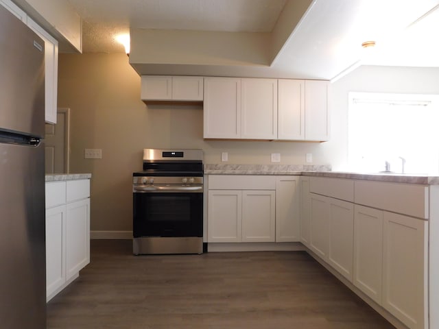 kitchen with light stone countertops, stainless steel appliances, white cabinetry, and dark wood-type flooring