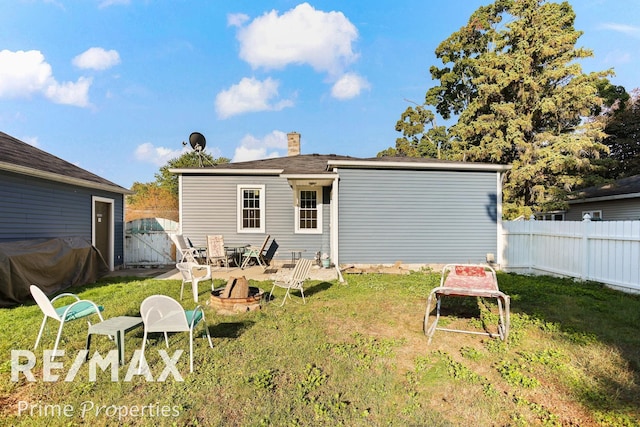 rear view of property with a yard and an outdoor fire pit