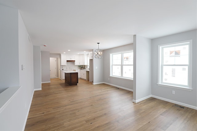 unfurnished living room featuring sink, light hardwood / wood-style flooring, and a chandelier