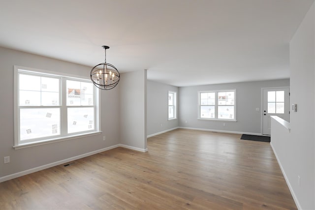 unfurnished room with hardwood / wood-style flooring, plenty of natural light, and an inviting chandelier