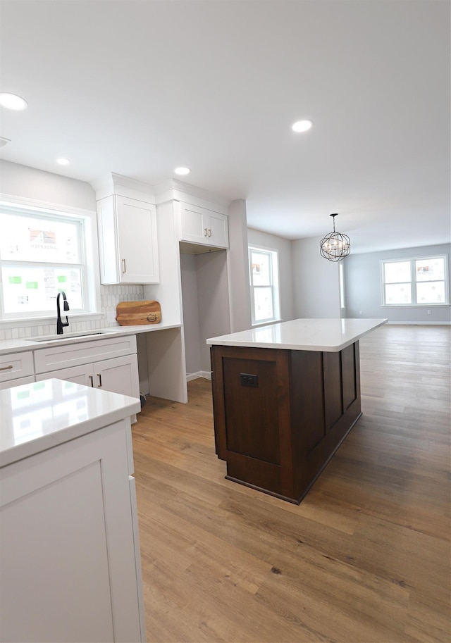 kitchen featuring sink, decorative light fixtures, a center island, and white cabinets