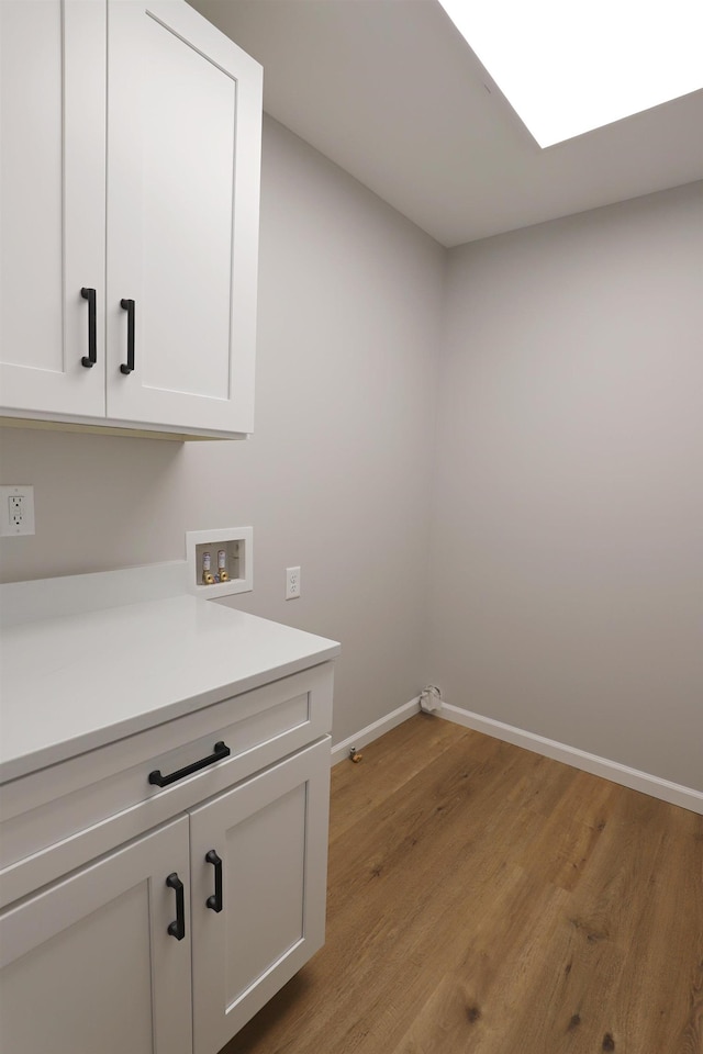 laundry room with cabinets, hookup for a washing machine, and light wood-type flooring