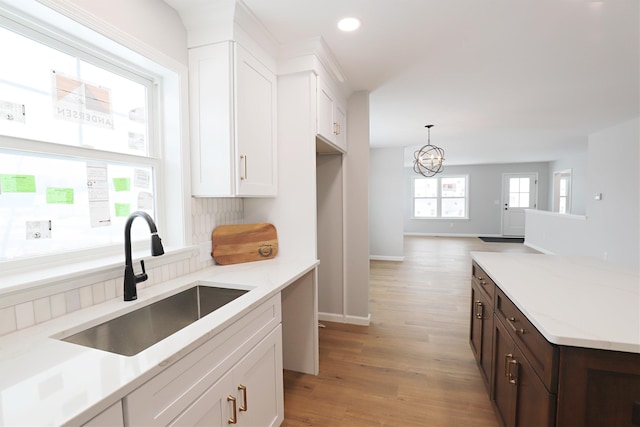 kitchen with white cabinetry, sink, light stone counters, and light hardwood / wood-style floors