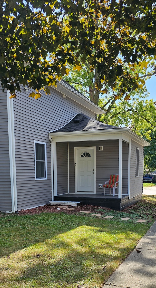 doorway to property featuring covered porch and a yard