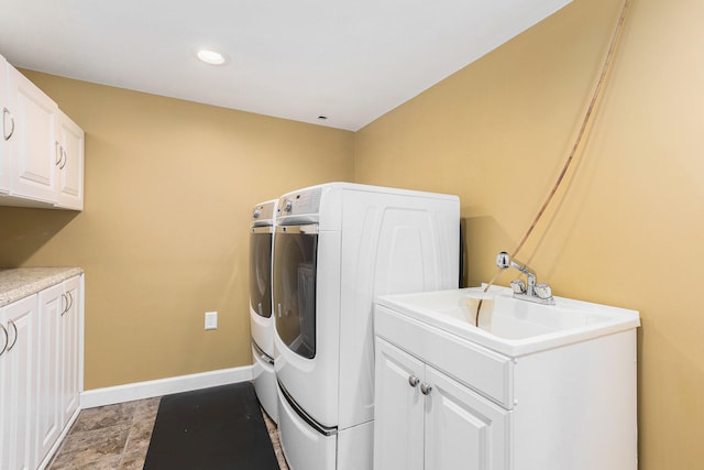 clothes washing area featuring cabinets, sink, and washer and dryer