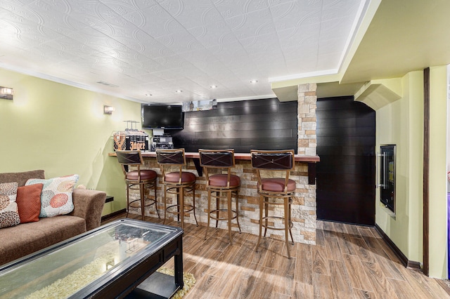 bar featuring ornamental molding, beverage cooler, and hardwood / wood-style flooring