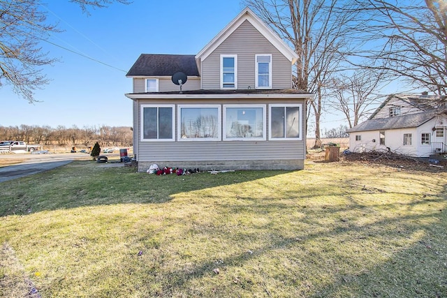 rear view of house with a yard and a sunroom