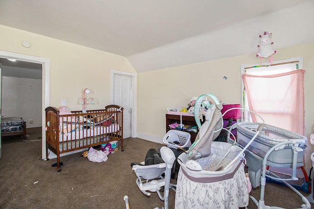 bedroom with a nursery area, vaulted ceiling, and dark colored carpet