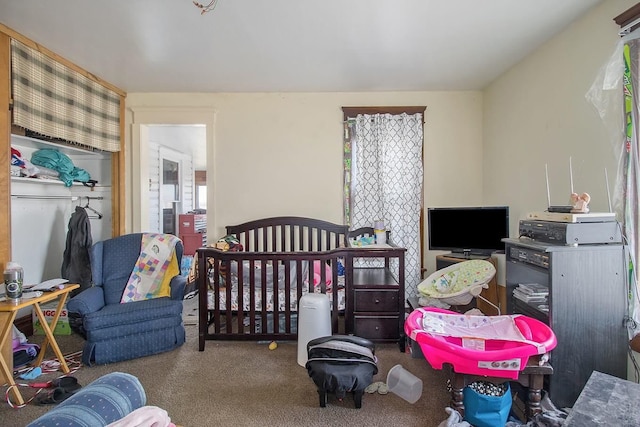 carpeted bedroom featuring multiple windows and a nursery area