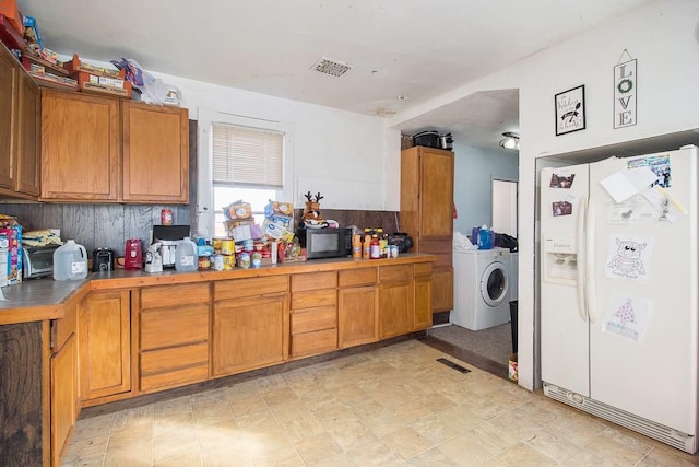 kitchen featuring washer / clothes dryer and white fridge with ice dispenser