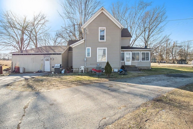 back of house with central air condition unit and a sunroom