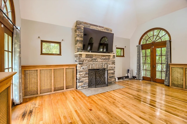 unfurnished living room with french doors, a fireplace, wood-type flooring, and vaulted ceiling