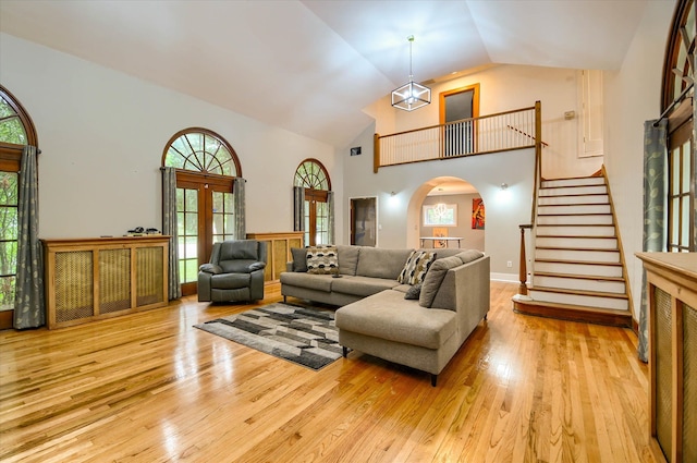 living room featuring french doors, high vaulted ceiling, and light hardwood / wood-style flooring