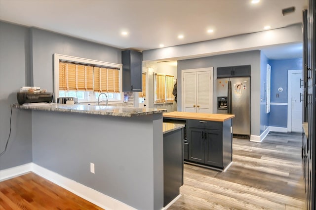 kitchen featuring wood counters, a center island, sink, light hardwood / wood-style floors, and stainless steel fridge with ice dispenser