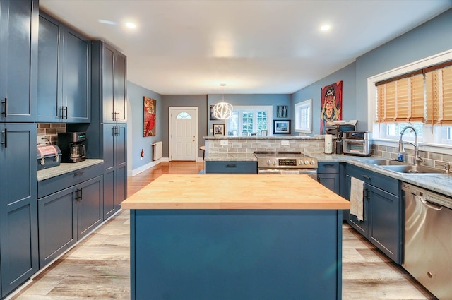 kitchen featuring appliances with stainless steel finishes, a kitchen island, plenty of natural light, and sink