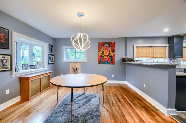 dining area featuring light wood-type flooring, sink, and an inviting chandelier