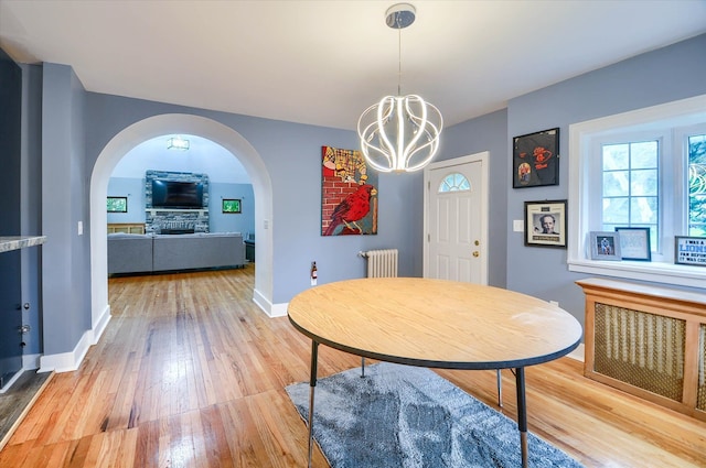 dining room with a chandelier, radiator heating unit, a fireplace, and hardwood / wood-style floors