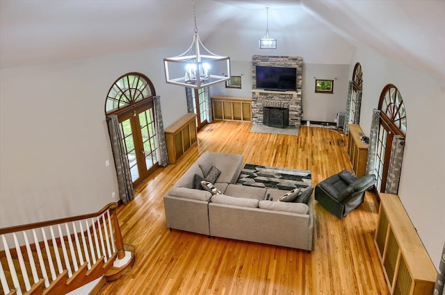 living room featuring french doors, vaulted ceiling, wood-type flooring, an inviting chandelier, and a fireplace