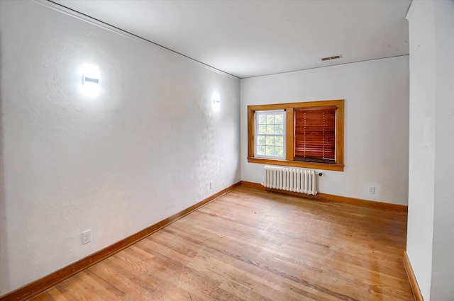 unfurnished room with radiator heating unit, light hardwood / wood-style floors, and crown molding